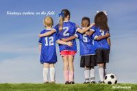 kids in soccer field showing kindness on soccer field with their arms around each other