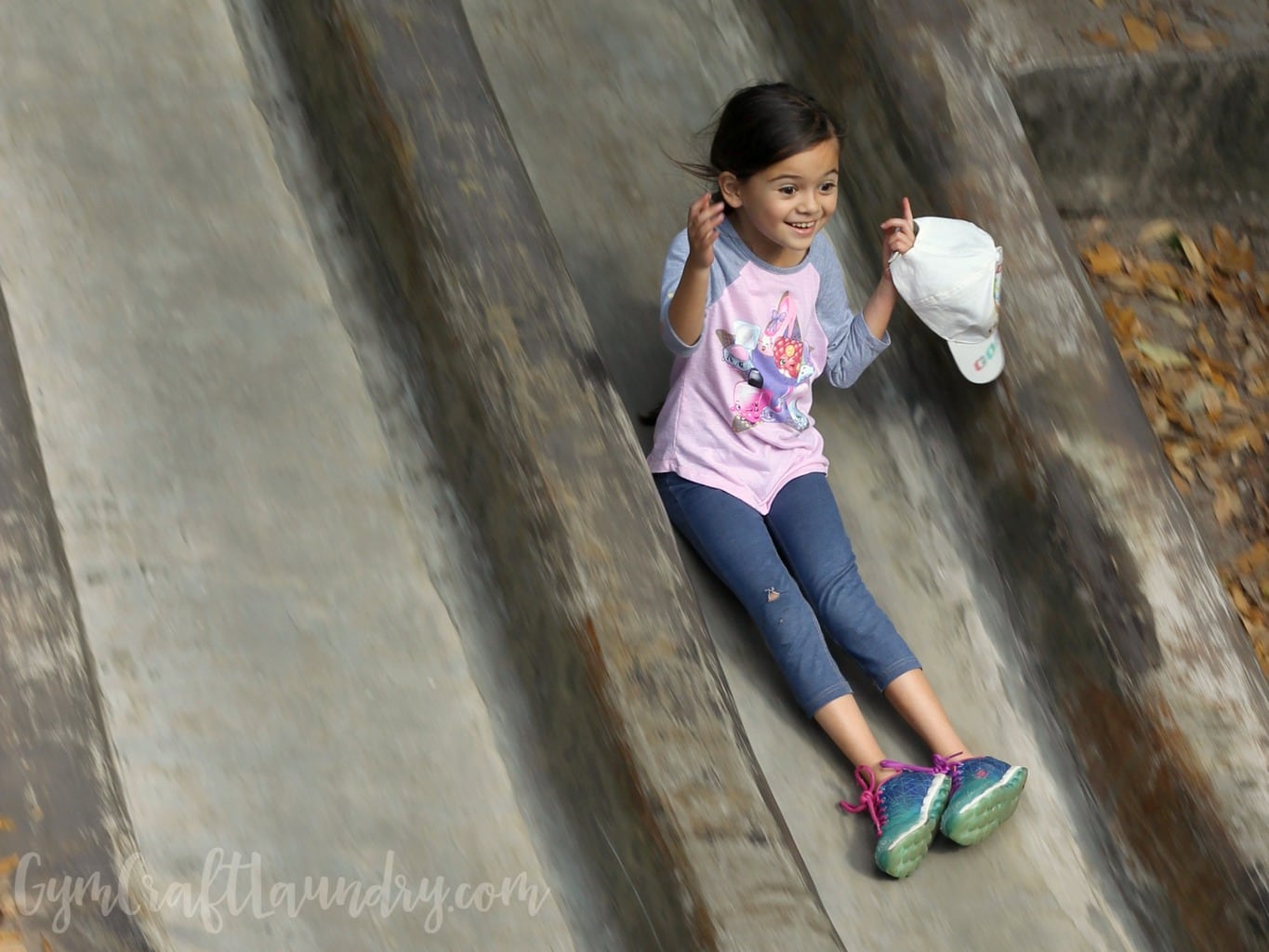 Girl sliding down the slide while playing outdoors.
