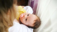 mom sitting on couch holding newborn during c-section recovery at home