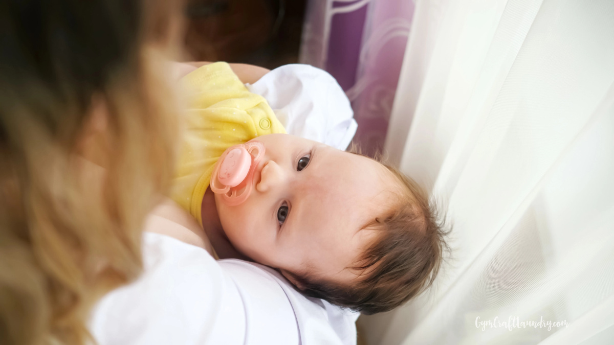 mom sitting on couch holding newborn during c-section recovery at home